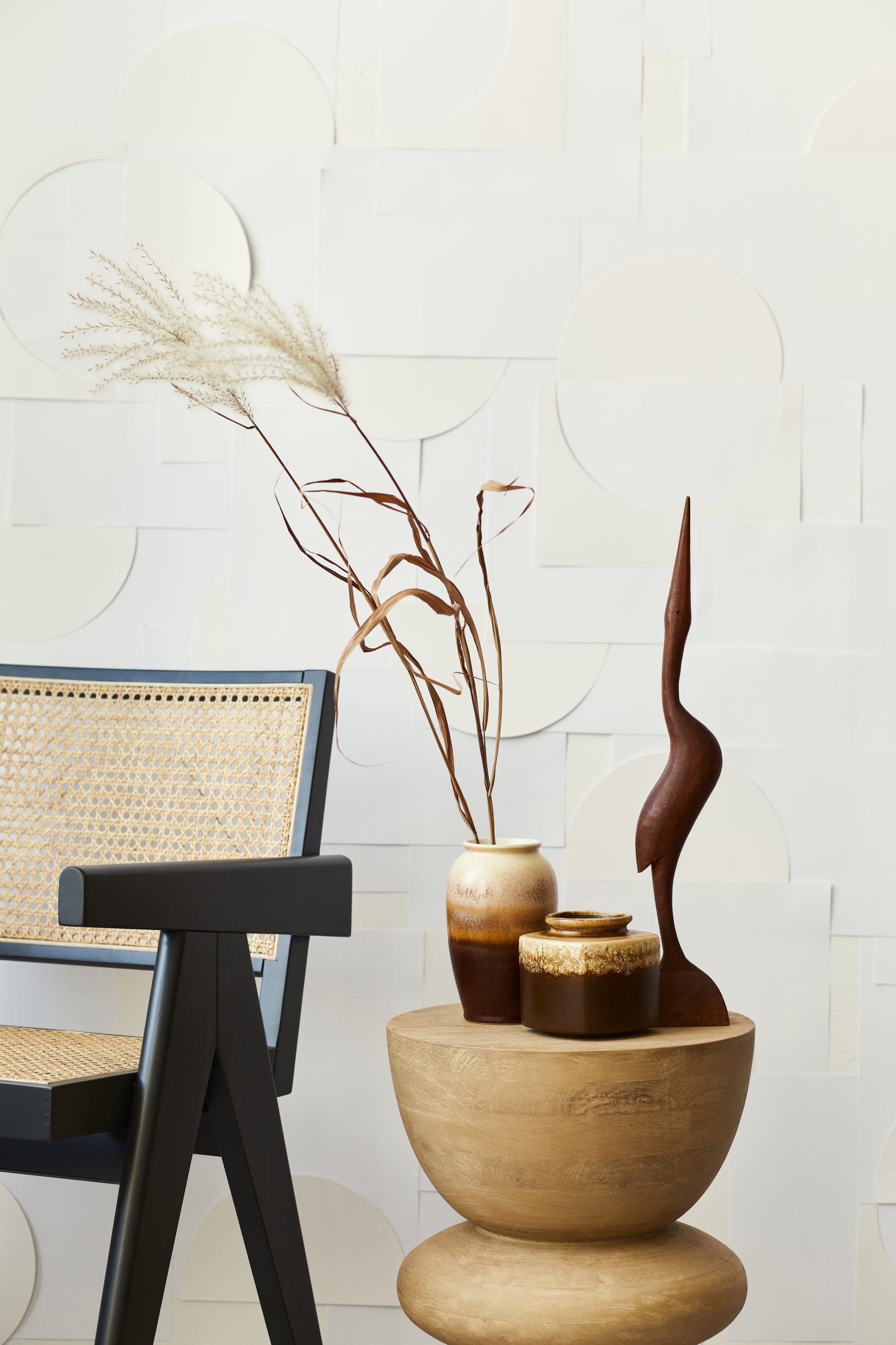 Stylish composition of white living room interior with design chair, beige wooden stool, dried flowers in vase and mock up art paintings on the wall. Template.